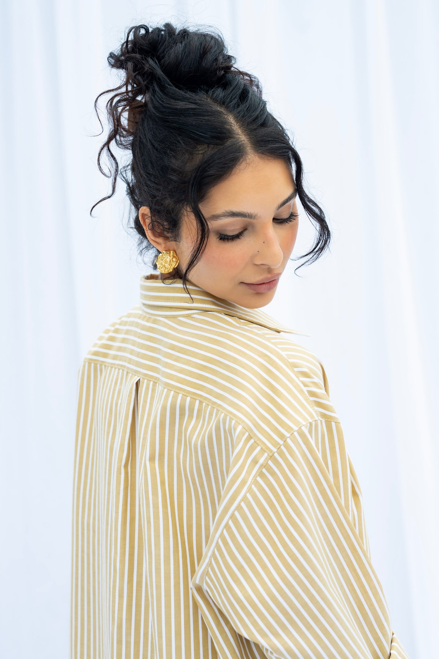 Woman wearing a beige and white striped shirt against a white background
