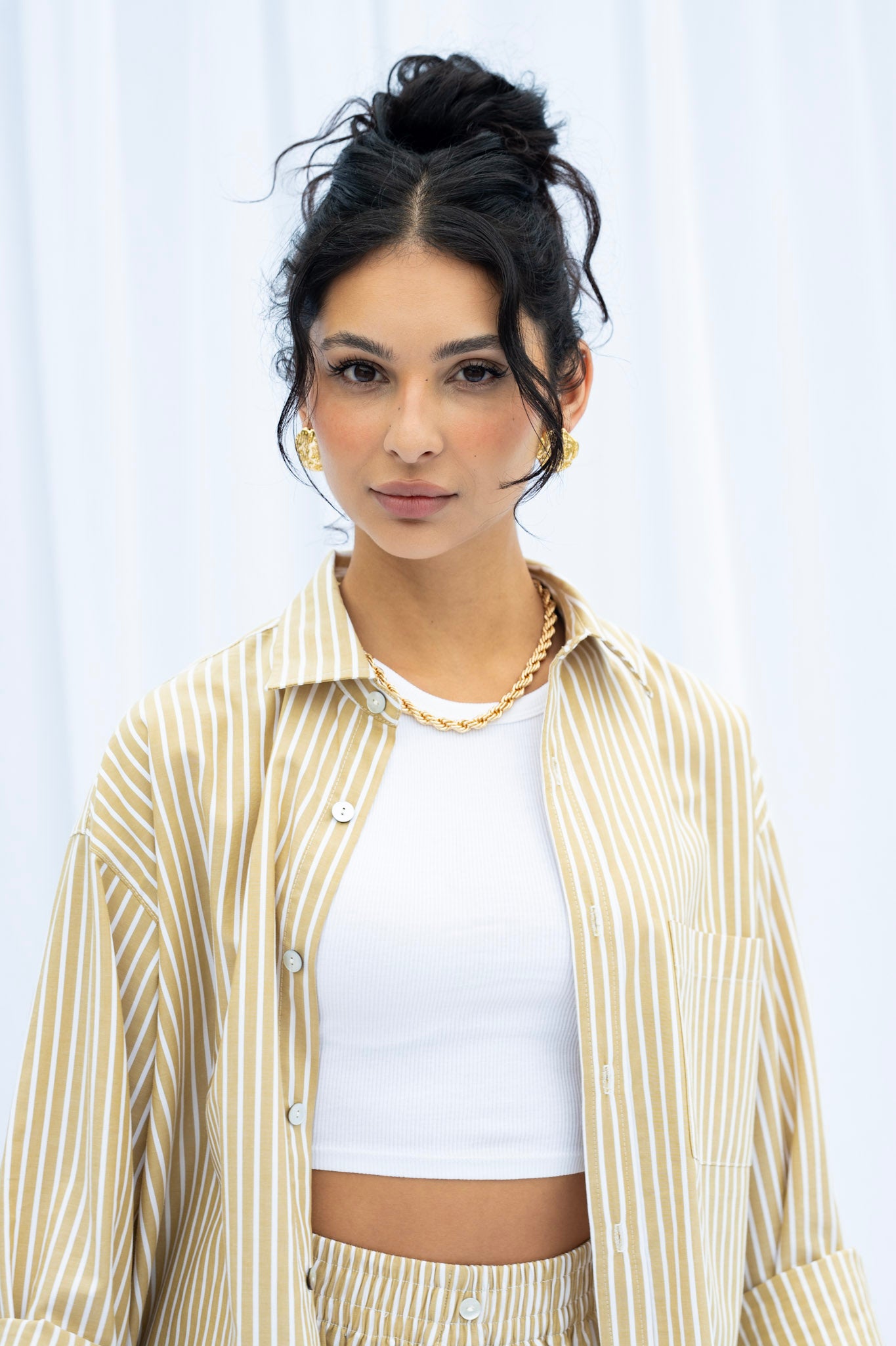 Woman wearing a striped shirt over a white top with a plain background
