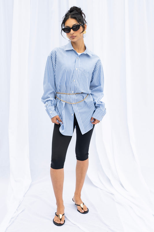 Woman wearing a blue and white striped shirt with black leggings on a white background