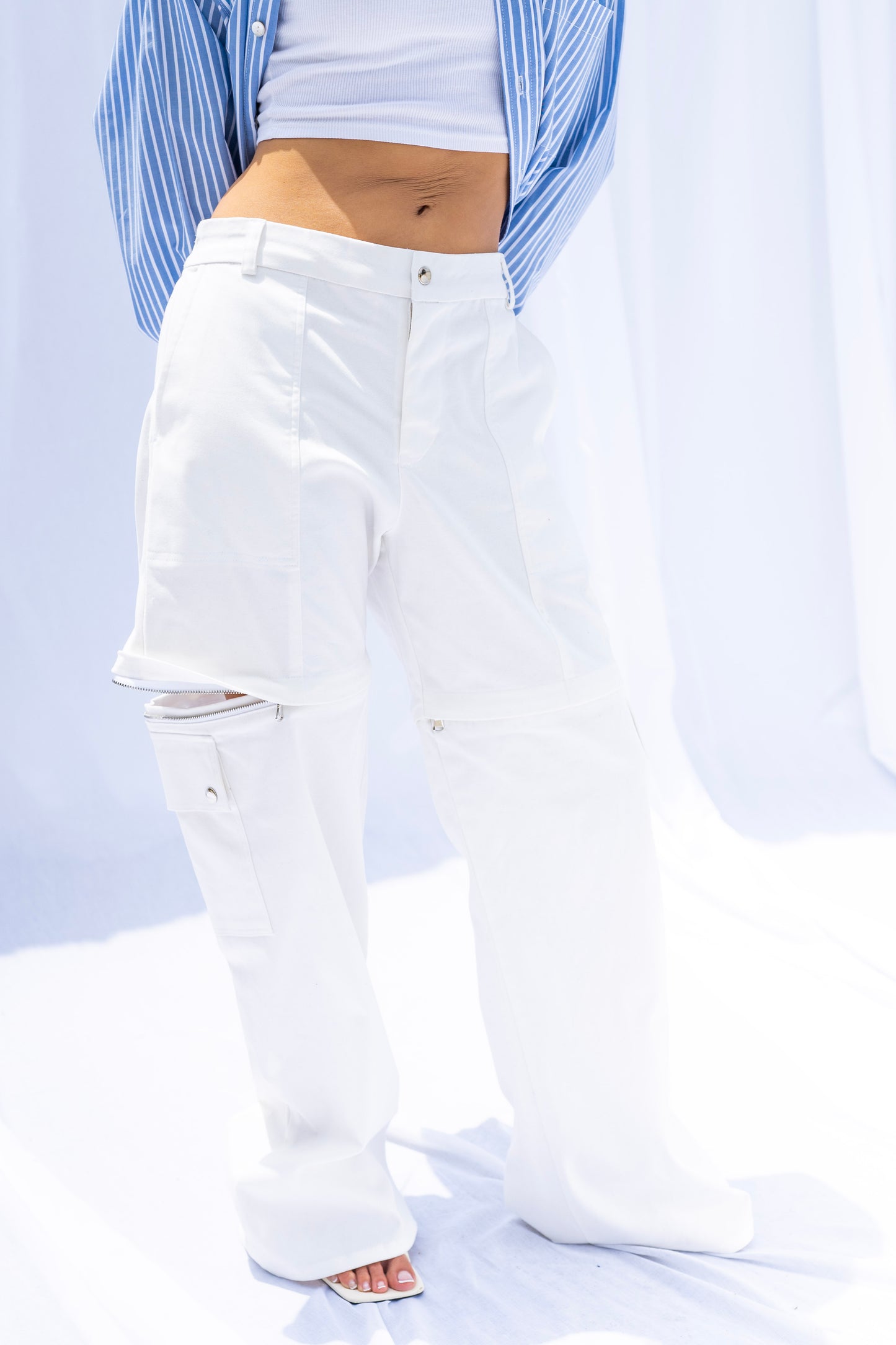 White pants worn by a person with a light blue shirt over a white top on a light gray background