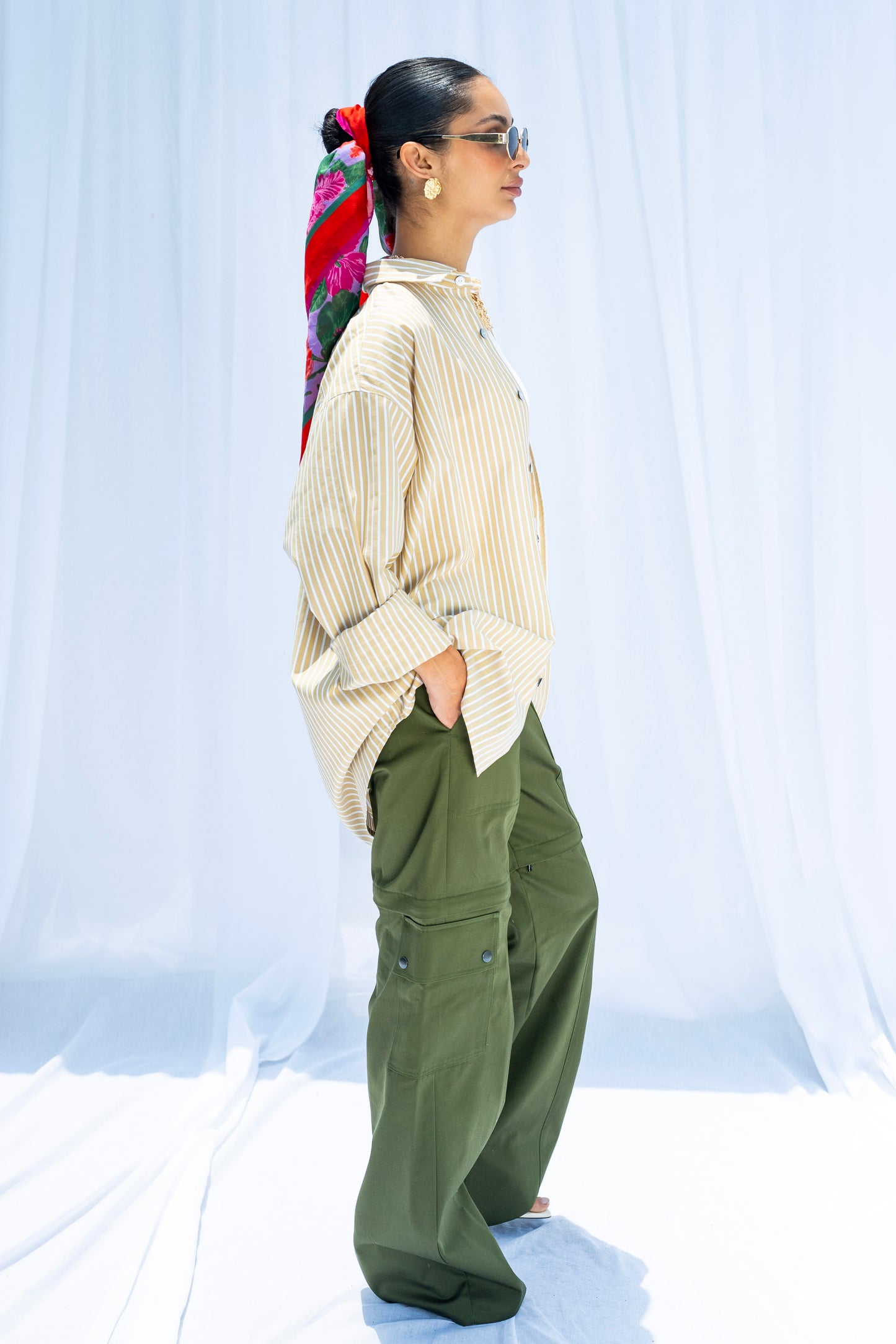 Person wearing a cream sweater and green pants against a white background