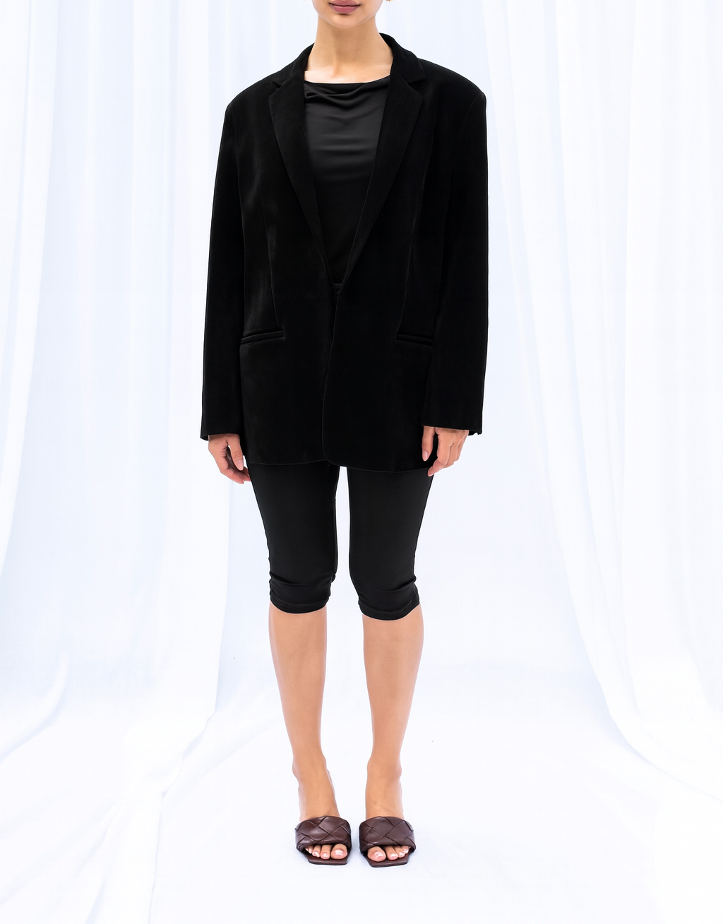 Person wearing a black blazer and black pants on a white background