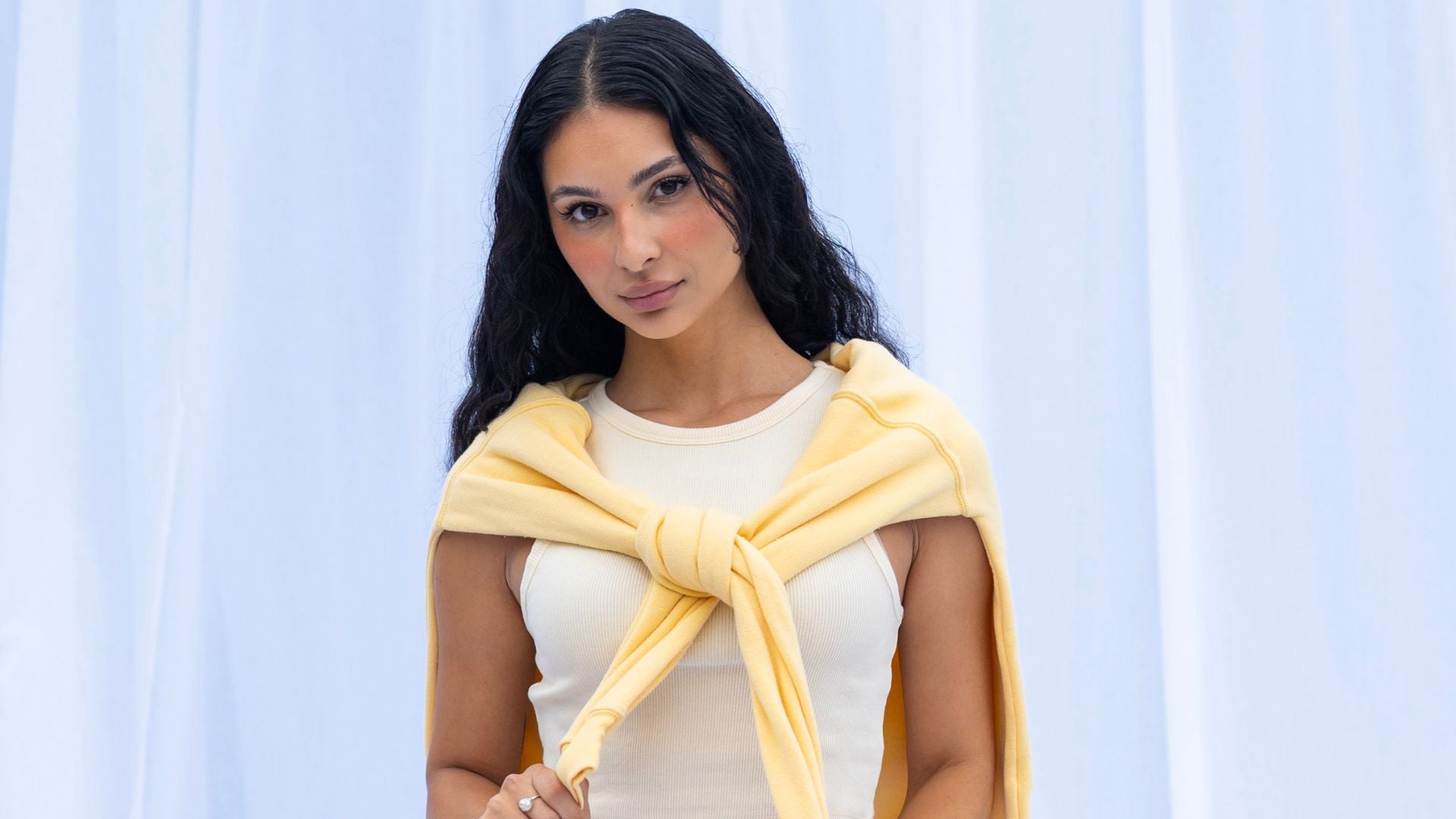 Woman wearing a yellow scarf against a light blue curtain background