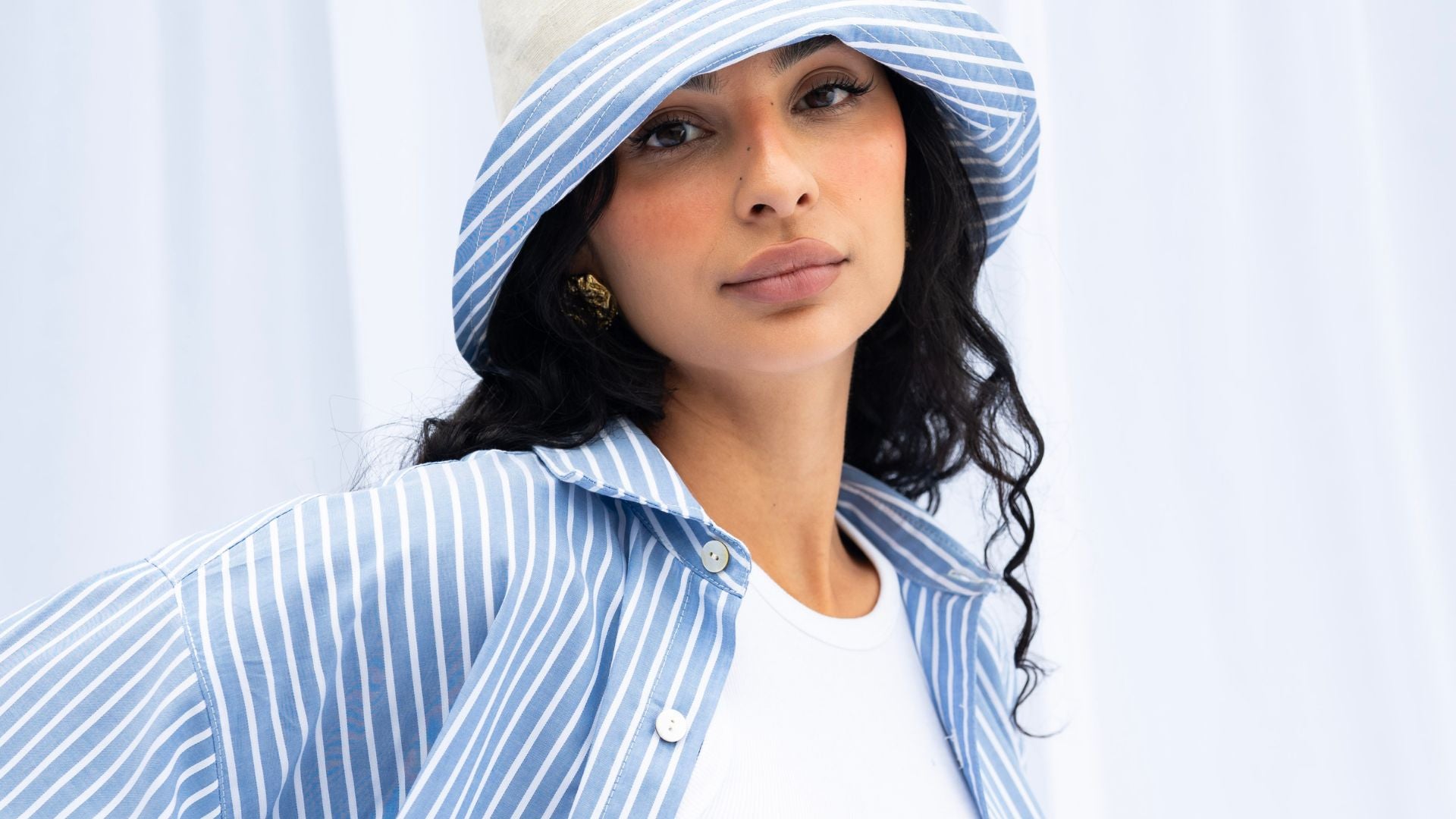 Woman wearing a blue and white striped hat and shirt against a light background