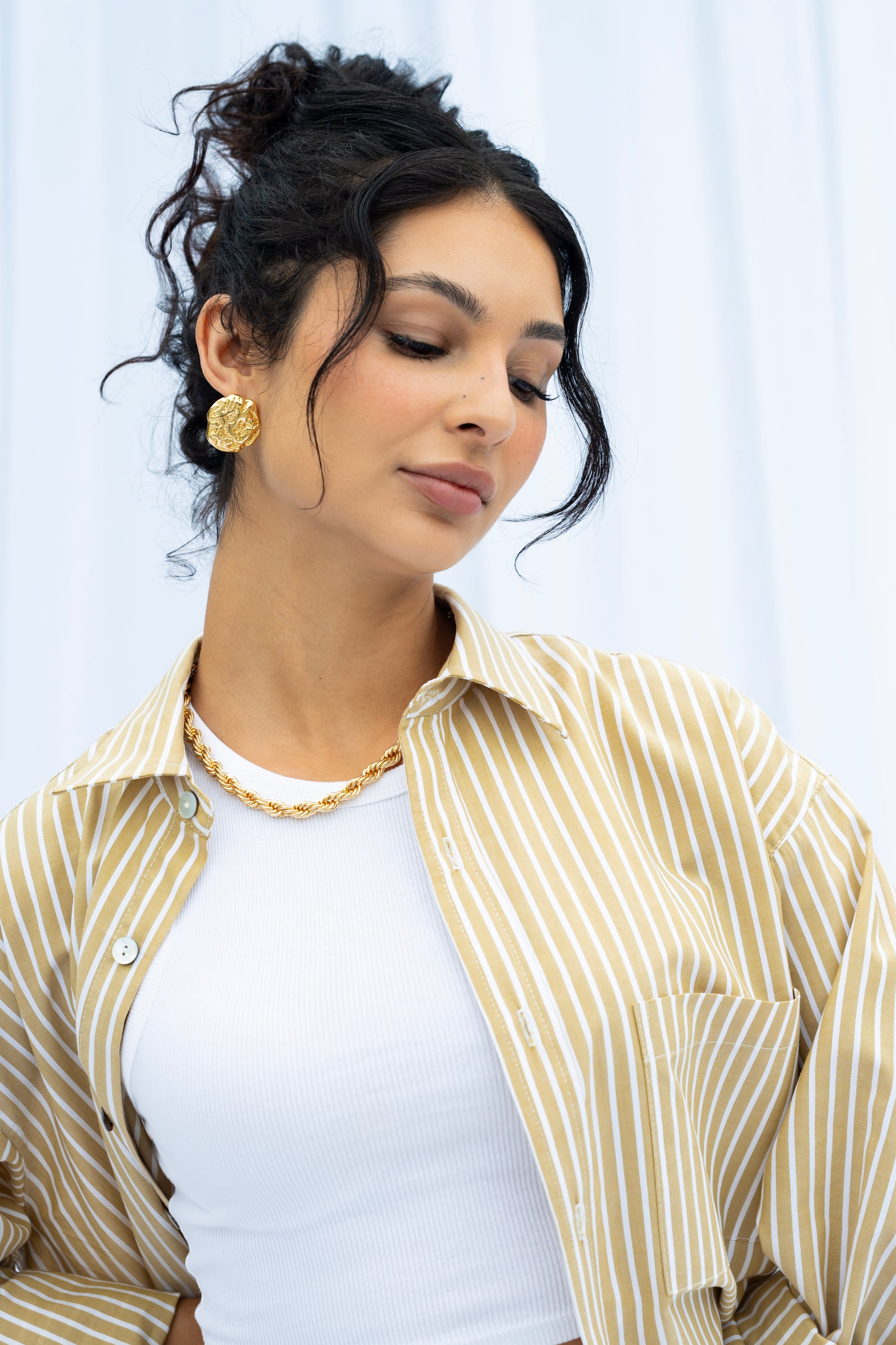 Woman wearing a striped shirt and white top with a neutral background