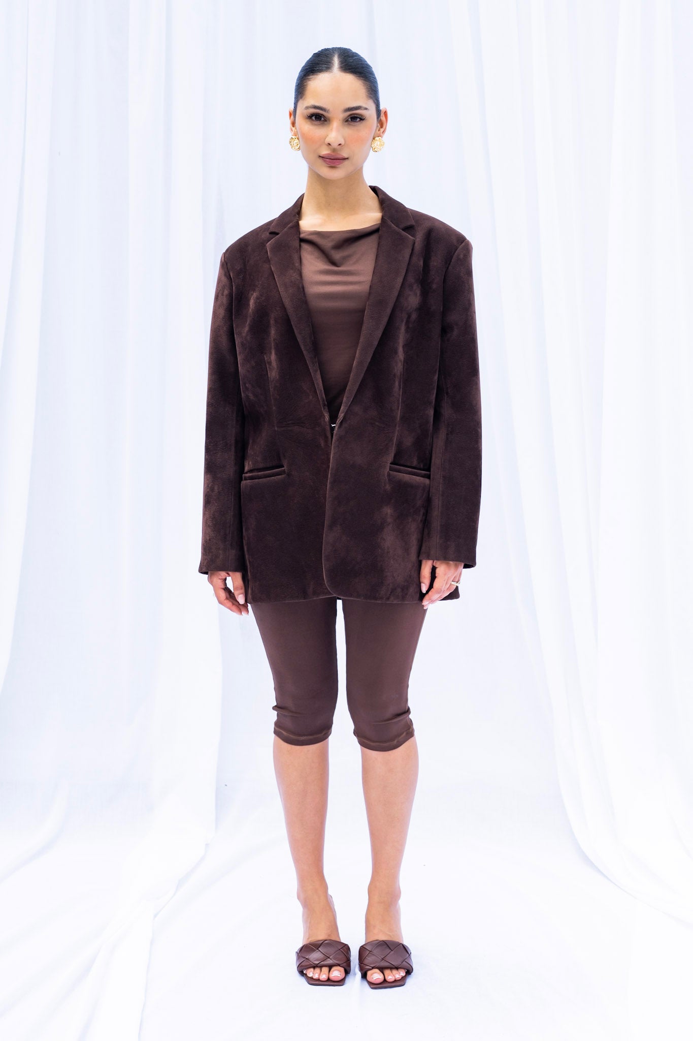 Woman wearing a brown blazer and pants on a white background