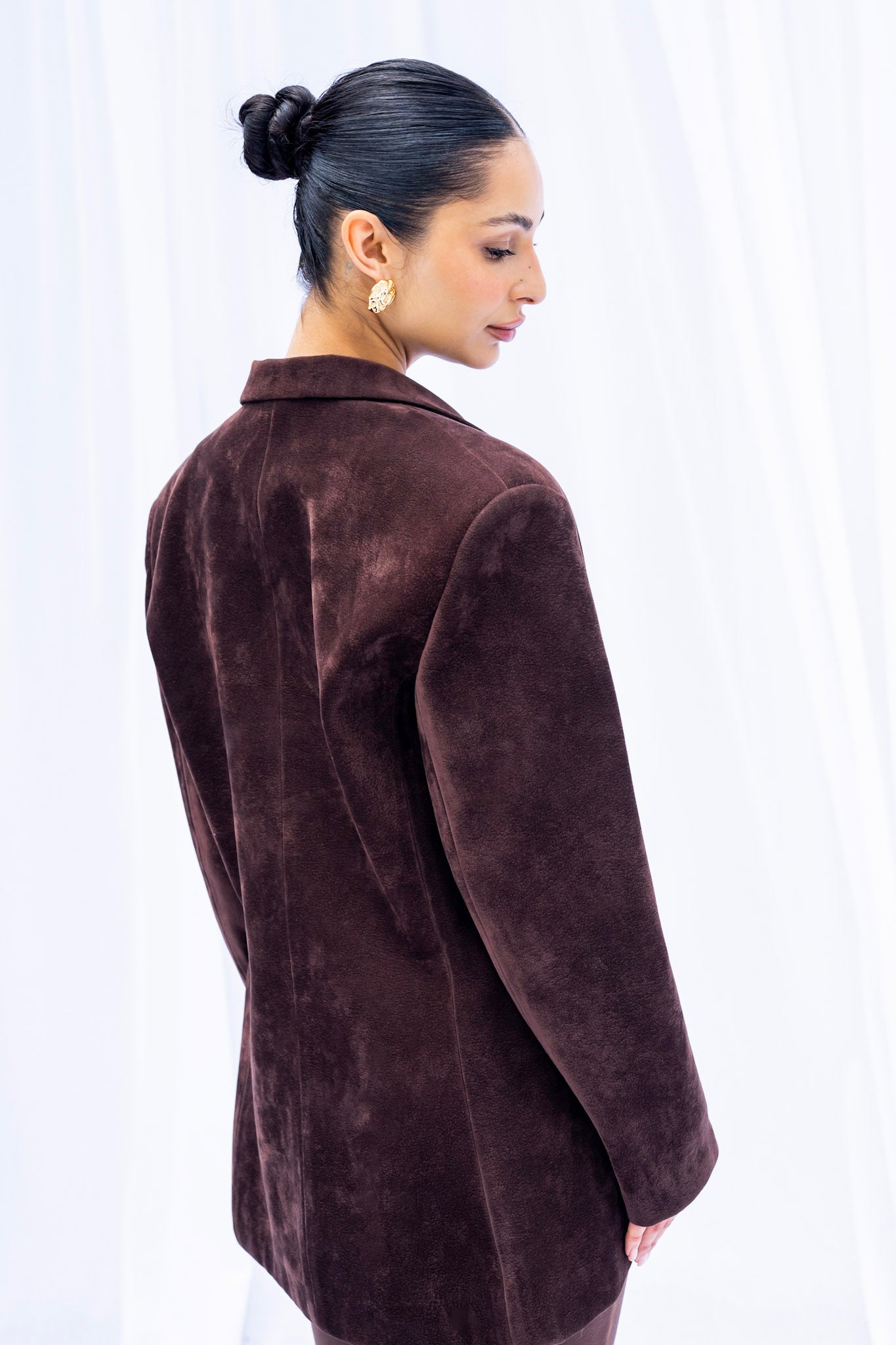 Woman wearing a brown velvet jacket against a white background