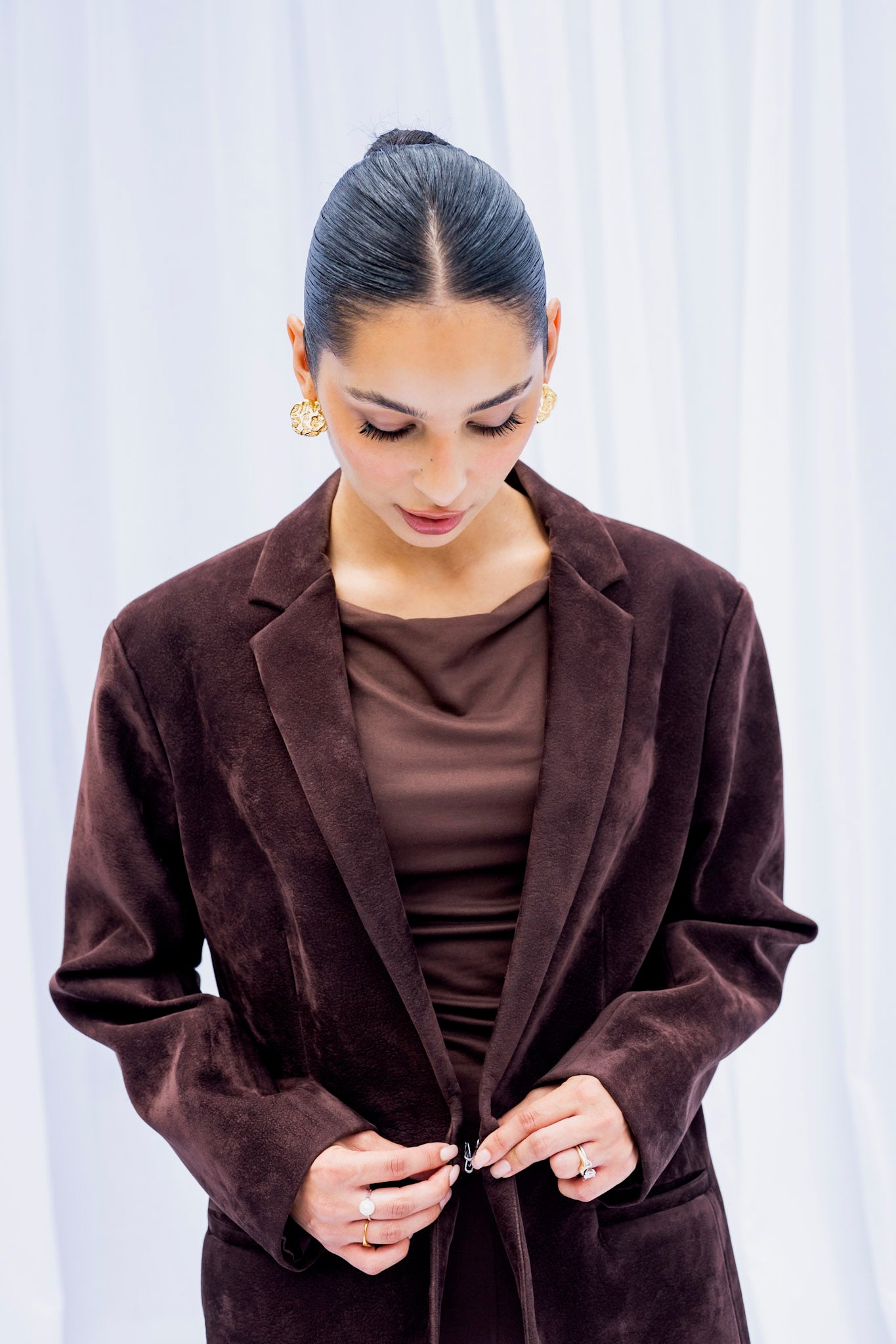 Woman wearing a brown blazer over a brown top against a white background