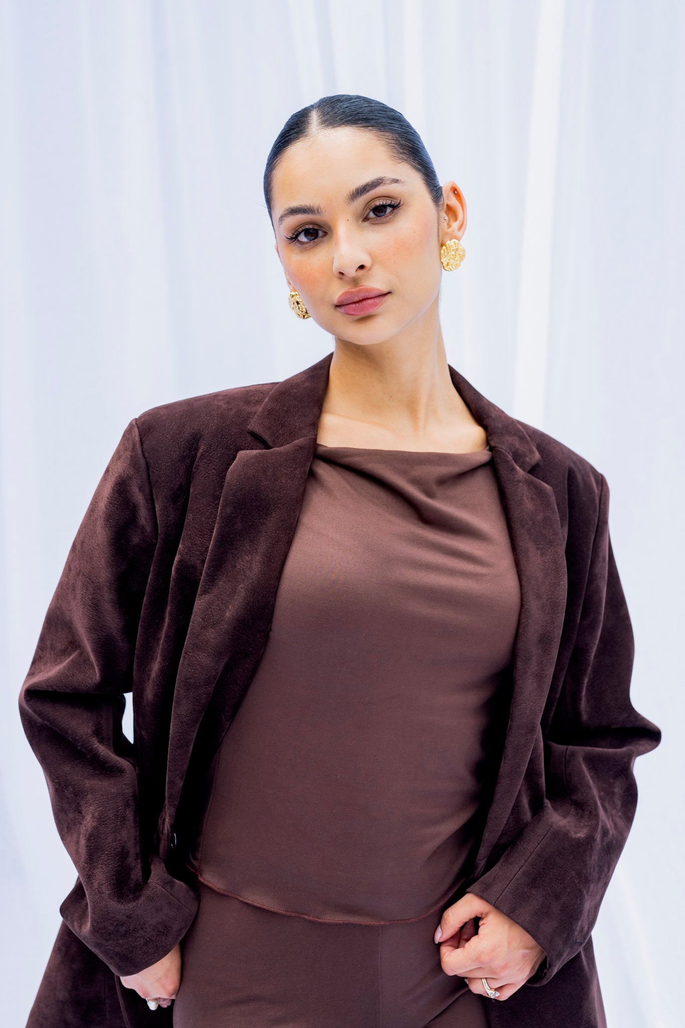 Woman wearing a brown jacket over a matching outfit against a white background